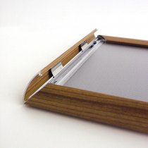 Närbild på öppnad snäpprofil i aluminium med träimitation för enkelt affischbyte