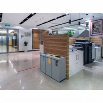 Källsorteringskärl i kontorsmiljö med färgkodade återvinningskärl