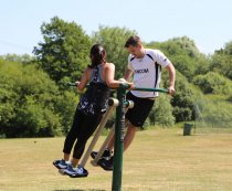 Personer som tränar på Air Skier utegym i parkmiljö.