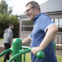 Person tränar vridövningar på Twister utegym i grön färg utomhus