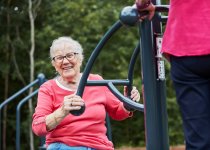 Senior tränar bålrotation med Twister utegym i offentlig träningsmiljö