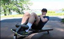 Man som utför situps på situpsbänk i utomhusgym.