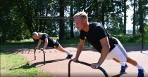 Armhävningar på Push Up Bars utegym – man och kvinna tränar överkropp utomhus